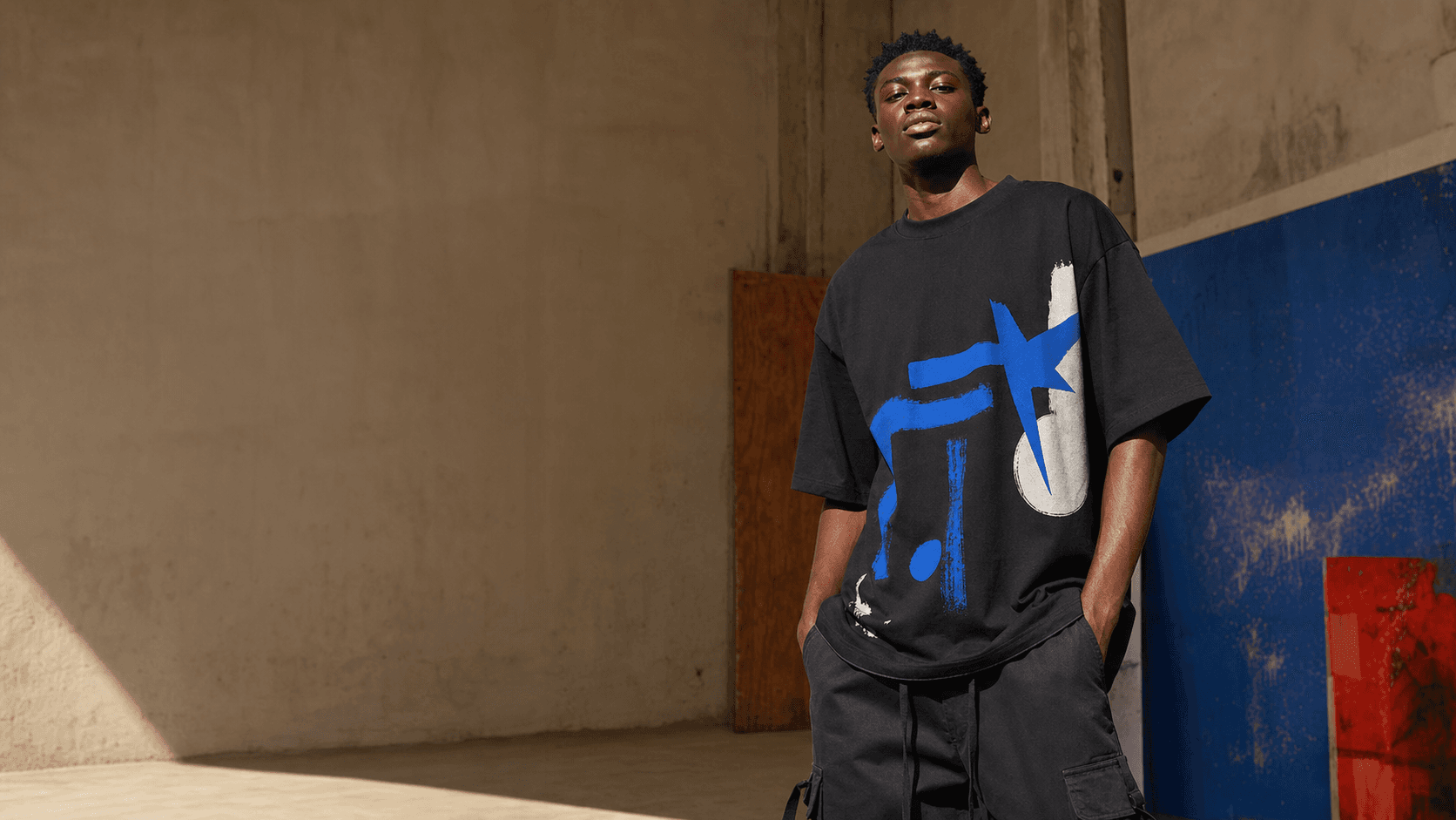 Demo model wearing a black custom graphic T-shirt in a cobalt-accented studio