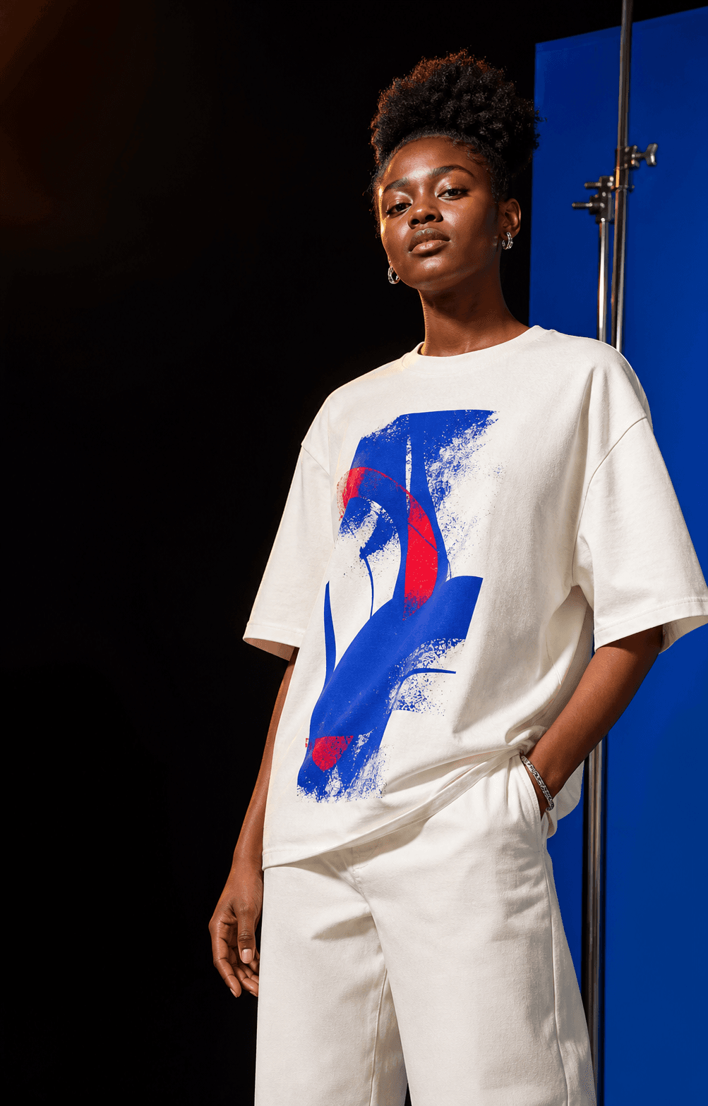 Demo model wearing a bone-white custom graphic T-shirt in a cobalt-accented studio