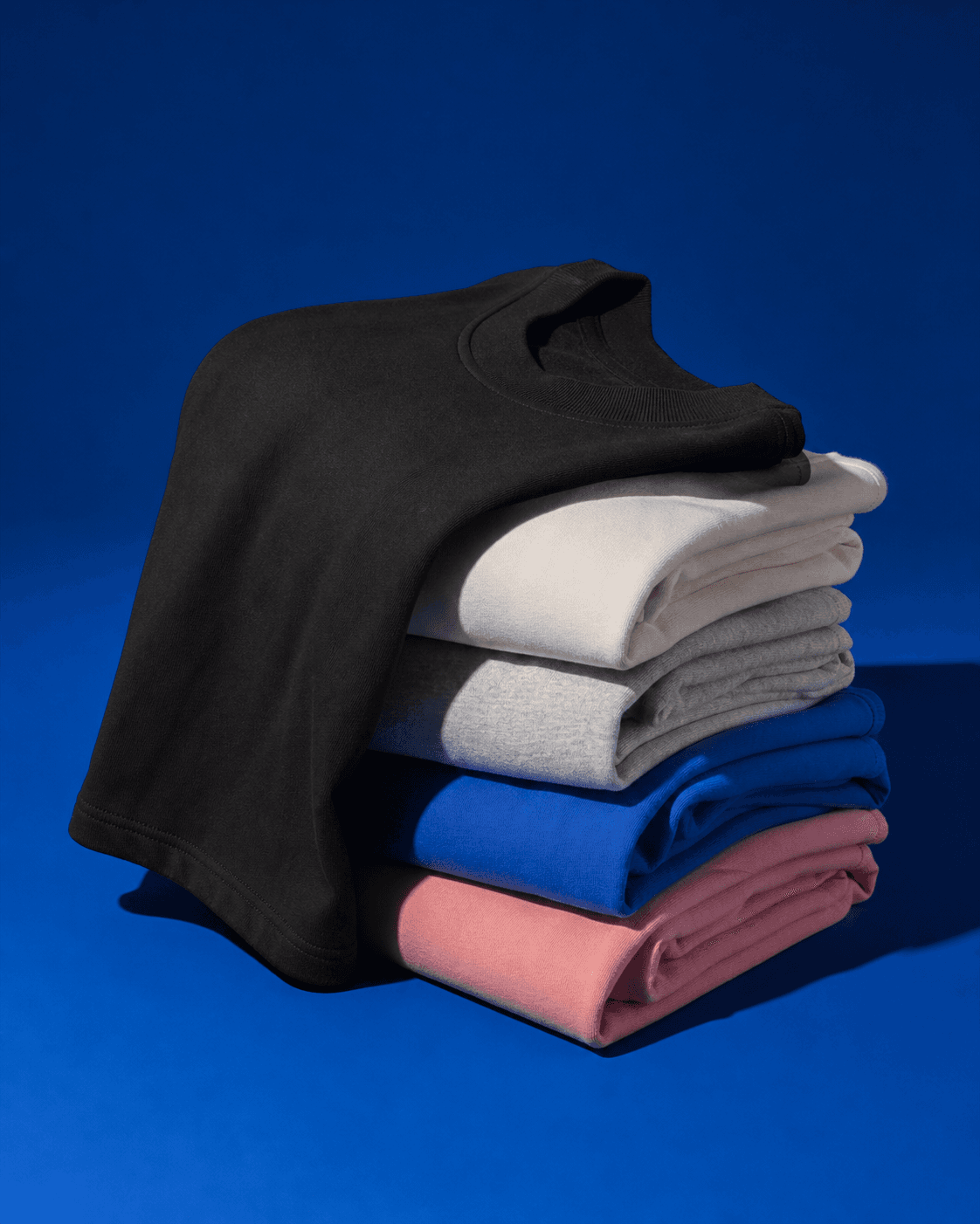 Folded stack of heavyweight blank T-shirts in multiple colours
